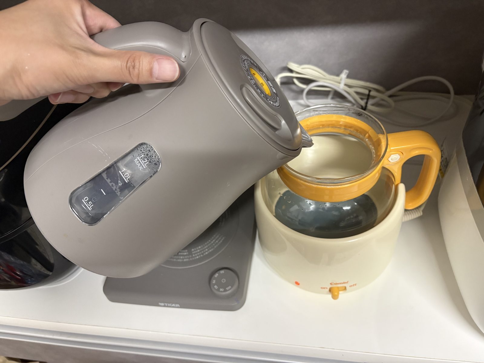 ケトルで沸かしたお湯を調乳じょーずのガラスポットに注いでいる手元