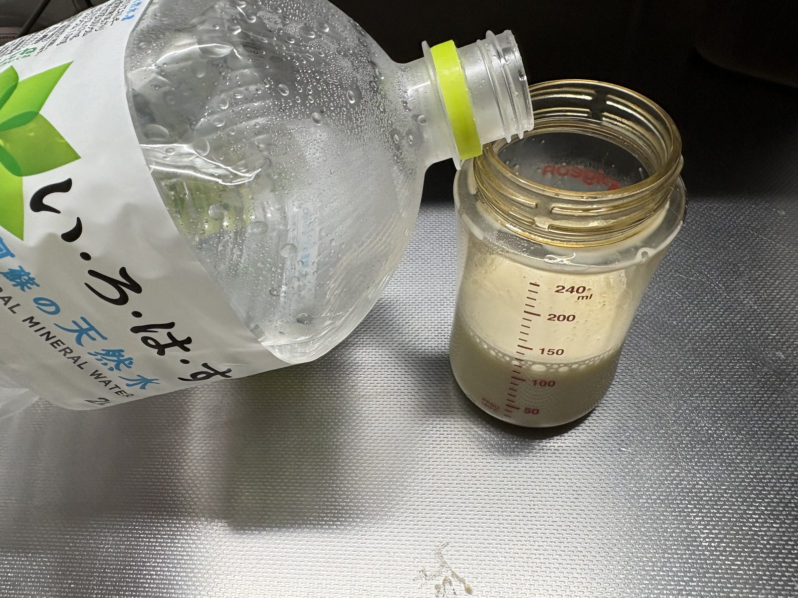 ミルクを溶かした哺乳瓶に軟水のペットボトルから冷まし水を足している様子